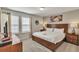 Spacious bedroom with a wood-framed bed, soft lighting, and large windows with blinds at 8840 Bengal Ct, Kissimmee, FL 34747