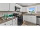 Functional kitchen with granite countertops, white cabinets, and black appliances, illuminated by a window with natural light at 3168 S Peninsula Dr, Daytona Beach, FL 32118