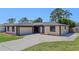Well-maintained single-story house with mature trees, featuring a spacious driveway leading to the garage at 5828 Westport Dr, Port Orange, FL 32127