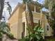 Two-story neutral home with balcony, shutters, and tropical foliage, offering curb appeal at 8639 Lower Villagewalk Cir, Orlando, FL 32827