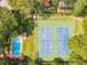 Aerial view of a backyard with a private pool and tennis court, surrounded by trees at 1 W Village Dr, Oviedo, FL 32765