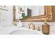 Elegant bathroom featuring double sinks, gold faucets, and an ornate mirror at 1 W Village Dr, Oviedo, FL 32765