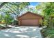 A spacious two-car garage is set back from the street, surrounded by lush greenery and mature trees at 1 W Village Dr, Oviedo, FL 32765