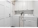 Well-organized laundry room with front loading washer and dryer and overhead cabinets at 1 W Village Dr, Oviedo, FL 32765