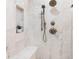 Close up of walk-in shower with marble tiling, bench, and shower head with handheld at 1 W Village Dr, Oviedo, FL 32765