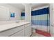 Bright bathroom featuring a white vanity with a quartz countertop and blue and white shower curtain at 10684 Words Dr, Winter Garden, FL 34787