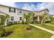 Inviting two-story townhome featuring a lush green lawn and neutral exterior tones, accented by dark shutters at 10684 Words Dr, Winter Garden, FL 34787