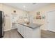 Large kitchen island with gray countertop, white cabinets, and a stainless steel refrigerator at 10684 Words Dr, Winter Garden, FL 34787