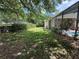 A partially shaded backyard with green grass, mature trees, and a screened-in patio at 12238 Still Meadow Dr, Clermont, FL 34711