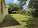 Side yard with green grass, privacy hedges, and shade provided by mature trees at 12238 Still Meadow Dr, Clermont, FL 34711