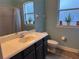 Bright bathroom with a sink vanity, toilet, and decorative plants by the windows at 12238 Still Meadow Dr, Clermont, FL 34711