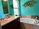 Bathroom features a soaking tub beneath a window, vanity with marble top and contemporary light fixture at 12238 Still Meadow Dr, Clermont, FL 34711