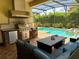 Outdoor kitchen and comfortable lounge seating overlooking the beautiful pool at 12238 Still Meadow Dr, Clermont, FL 34711