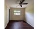 A cozy bedroom featuring dark wood floors, a window, a ceiling fan, and a neutral color scheme at 1528 Baltimore Dr, Orlando, FL 32810