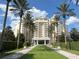 Elegant resort-style building with lush landscaping and stately palm trees under a bright blue sky at 1554 Corolla Ct, Reunion, FL 34747