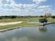 Picturesque golf course featuring a scenic lake, sand traps, and neatly manicured green under a blue sky and clouds at 1554 Corolla Ct, Reunion, FL 34747