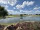 Expansive view of the community lake with fountain and an adjacent golf course against a partly cloudy sky at 1554 Corolla Ct, Reunion, FL 34747