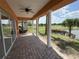 Covered patio view of the lake and golf course with towering columns, brick pavers, lush landscaping and palm trees at 1554 Corolla Ct, Reunion, FL 34747