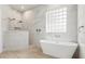 A luxurious bathroom featuring a standalone tub, glass block window, and marble tiled walls at 205 Torcaso Ct, Winter Springs, FL 32708
