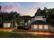 Beautiful two-story home with a well-manicured lawn, red mulch, and mature trees at dusk at 205 Torcaso Ct, Winter Springs, FL 32708