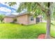 View of the rear of a tan home with lush green lawn, large shade tree, and covered patio at 2724 Westyn Cove Ln, Ocoee, FL 34761