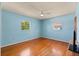 Bright bedroom with two windows, wood floors, ceiling fan, and soothing blue walls at 2906 E Grant Ave, Orlando, FL 32806