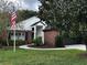Charming brick and white home with an American flag and well-manicured lawn and 2-car garage at 3063 Ash Park Loop, Winter Park, FL 32792