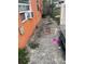 Narrow side yard featuring a weathered walkway alongside the orange home's exterior at 330 S Buena Vista Ave, Orlando, FL 32835