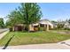 Beautifully landscaped front yard with mature trees and green lawn, with yellow home exterior and awnings at 335 W Bay St, Winter Garden, FL 34787