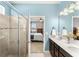 Bathroom featuring dual sinks, a tile shower with glass door, and a glimpse into the bedroom at 3632 Gretchen Dr, Ocoee, FL 34761