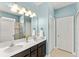Bright bathroom showcasing a dual sink vanity, large mirror with decorative lighting, and a tiled floor at 3632 Gretchen Dr, Ocoee, FL 34761