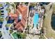 An aerial view showcases a community pool with lounge chairs, cabanas, a building with a red tile roof, and lush landscaping at 4569 Cabello Loop, Kissimmee, FL 34746