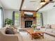Inviting living room features a cozy brick fireplace, beamed ceiling, and plush neutral furniture at 4887 Seminole Ave, Winter Park, FL 32792