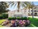 Attractive community sign nestled in lush landscaping including tropical palm trees and colorful flowers at 5550 E Michigan St # 2202, Orlando, FL 32822