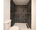 Modern bathroom featuring a dark-tiled shower with updated fixtures and toilet at 5578 Metrowest Blvd # 10, Orlando, FL 32811