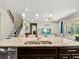 Kitchen island with sink and granite countertops, pendant lighting, and staircase to the second floor at 645 American Holly Pl, Oviedo, FL 32765