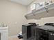 Modern laundry room featuring sleek black washer and dryer set and ample storage space on the shelving at 645 American Holly Pl, Oviedo, FL 32765