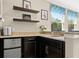 Granite countertop wet bar area with dark cabinetry, mini-fridge, and open shelving at 645 American Holly Pl, Oviedo, FL 32765