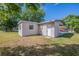 Cozy home features a well-maintained backyard with lush green grass, mature trees and a rear carport entrance at 73 Channing Ave, Orlando, FL 32811