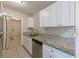 Galley kitchen with stainless steel appliances, white cabinets, and granite countertops at 73 Channing Ave, Orlando, FL 32811