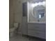 Modern bathroom vanity, round mirror, and tiled floor at 8775 Sartori St # 302, Orlando, FL 32829