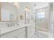 Bright bathroom features double sinks, white cabinets, marble countertops, and glass enclosed shower at 13638 Sunset Lakes Cir, Winter Garden, FL 34787