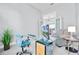 Sun-filled office space with glass desk, blue chair, and view to the adjoining living room at 13638 Sunset Lakes Cir, Winter Garden, FL 34787