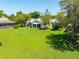 Expansive backyard with lush green lawn, mature trees, and a screened-in lanai at 203 Prestwick Dr, New Smyrna Beach, FL 32168
