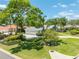 Well-manicured front yard with mature trees, green lawn, and a home featuring a spacious three-car garage at 203 Prestwick Dr, New Smyrna Beach, FL 32168