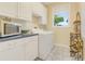 Bright laundry room features white cabinets, modern appliances, and a large window for natural light at 203 Prestwick Dr, New Smyrna Beach, FL 32168