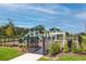 Community playground featuring a slide, climbing structure, and safety fence in a landscaped setting at 1090 Chelan Falls Dr, Deland, FL 32724