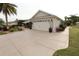 View of the home's exterior, featuring a spacious driveway, a two-car garage, and a well-manicured lawn at 1669 Plum Branch Ter, The Villages, FL 32162