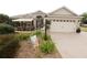 Inviting home featuring a well-maintained lawn, a two-car garage, and a cozy front porch with comfortable seating at 1669 Plum Branch Ter, The Villages, FL 32162