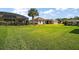 Expansive backyard features lush green grass, mature palm trees, and screened patios for outdoor enjoyment at 11041 Se 169Th Pl, Summerfield, FL 34491